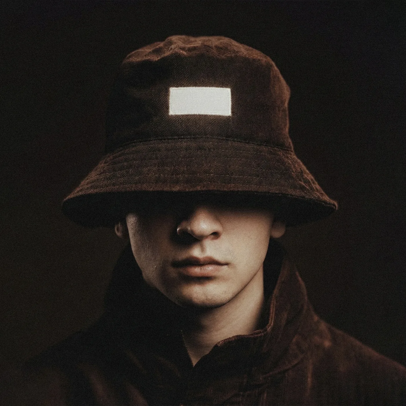 Retrato de Tommy Bueno con sombrero, luz cálida y expresión seria